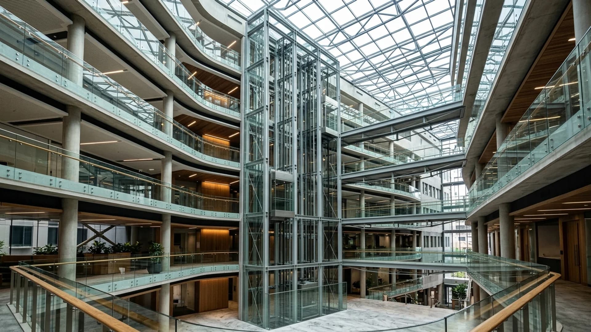 Bank of glass-walled passenger lifts rising through the atrium void of a multi-storey Australian commercial building lit by a skylight
